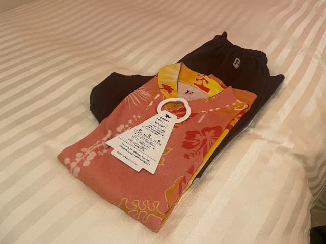 三井ガーデンホテルプラナ東京ベイのベッドの上に折りたたまれたナイトウェア